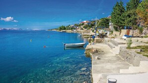 Une ville côtière aux eaux cristallines, avec un bateau amarré sur la plage et des maisons qui bordent le littoral.