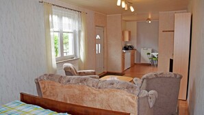 A bedroom with a bed, two armchairs, a small table, and a window with curtains. - Vacation apartment with garden terrace - Holiday apartments with terrace (Patzig)