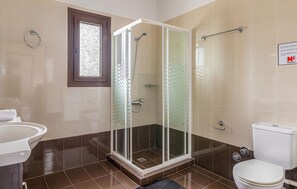 Moderni kylpyhuone, jossa on lasiseinällä varustettu suihku, pesuallas ja wc.
