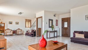 Ein geräumiges Wohnzimmer mit einem Holztisch, zwei Sesseln, einer Couch und einer Treppe, die zu einer weiteren Ebene führt.