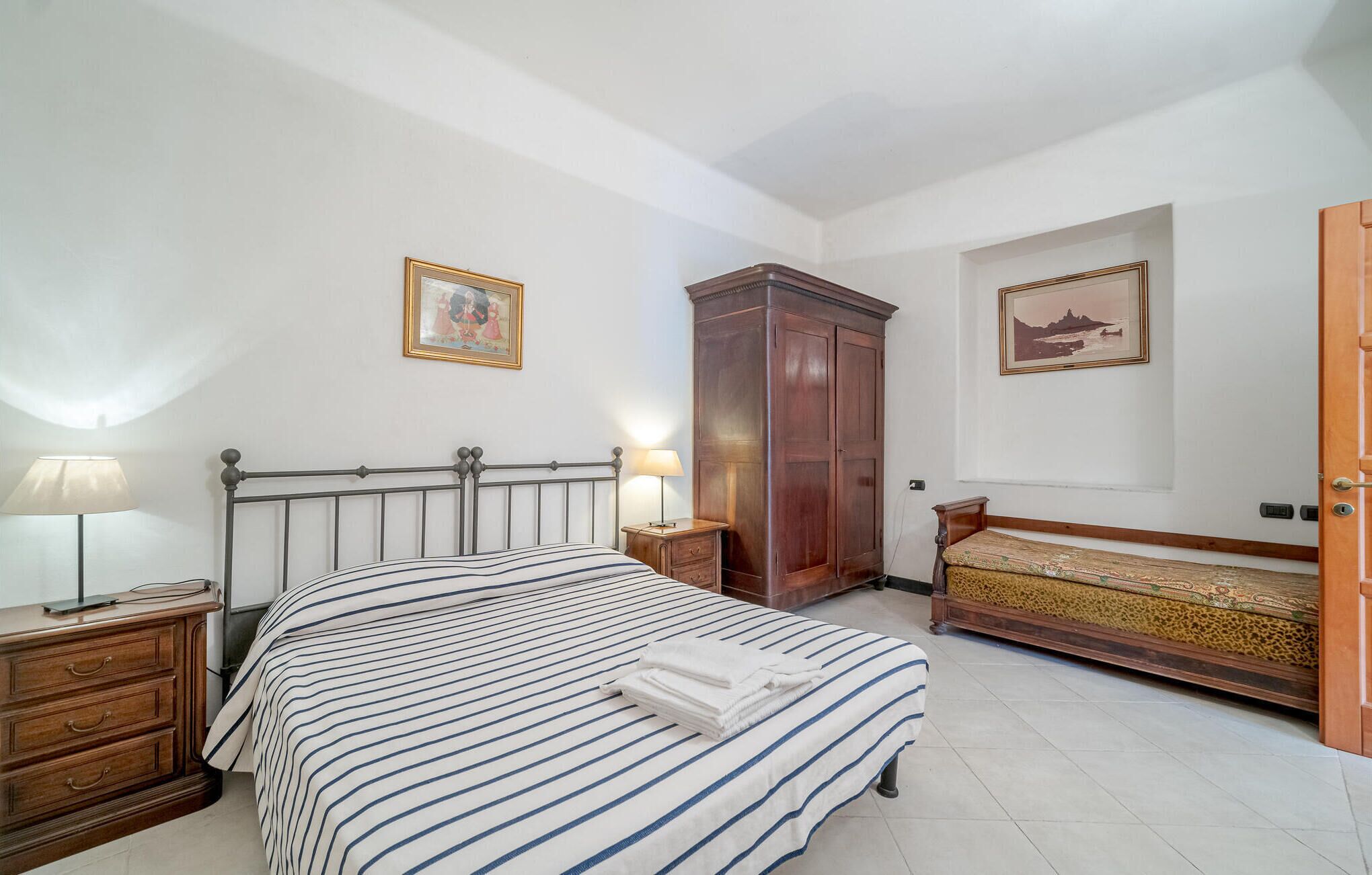 Una camera da letto con un letto, comodini, un armadio e due quadri appesi alle pareti.