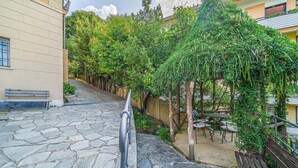A stone-paved pathway leading to a seating area with benches and a pergola covered in greenery. - Lovely apartment in Rapallo GE with WiFi (Rapallo GE)