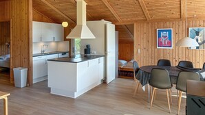 A modern kitchen with white cabinets, a central island, and a hanging light fixture. - Nice home in Sydals with sauna (Sydals)