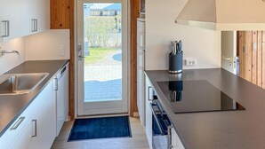 A modern kitchen with a stainless steel sink, wooden cabinets, and a black countertop. - Nice home in Sydals with sauna (Sydals)