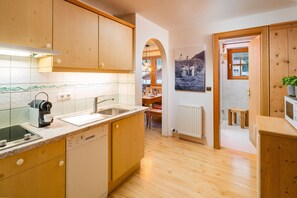 A kitchen with wooden cabinets, a dishwasher, a sink, and a countertop with a kettle and a coffee maker.
