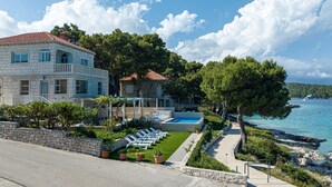 A coastal property with a pool, lounge chairs, and a view of the sea. - 4 bedroom amazing apartment in Lumbarda (Lumbarda)