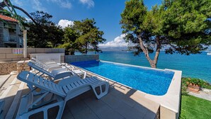 A swimming pool with lounge chairs, a view of the sea, and a building in the background. - 4 bedroom amazing apartment in Lumbarda (Lumbarda)