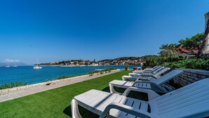 A seaside resort with white lounge chairs and a pool area. - 4 bedroom amazing apartment in Lumbarda (Lumbarda)