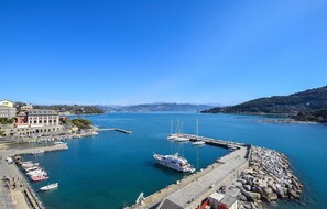 Un port de plaisance avec des bateaux amarrés, une digue rocheuse et des bâtiments en arrière-plan.