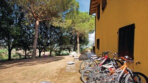 A courtyard with a yellow building, trees, and a row of bicycles parked outside.