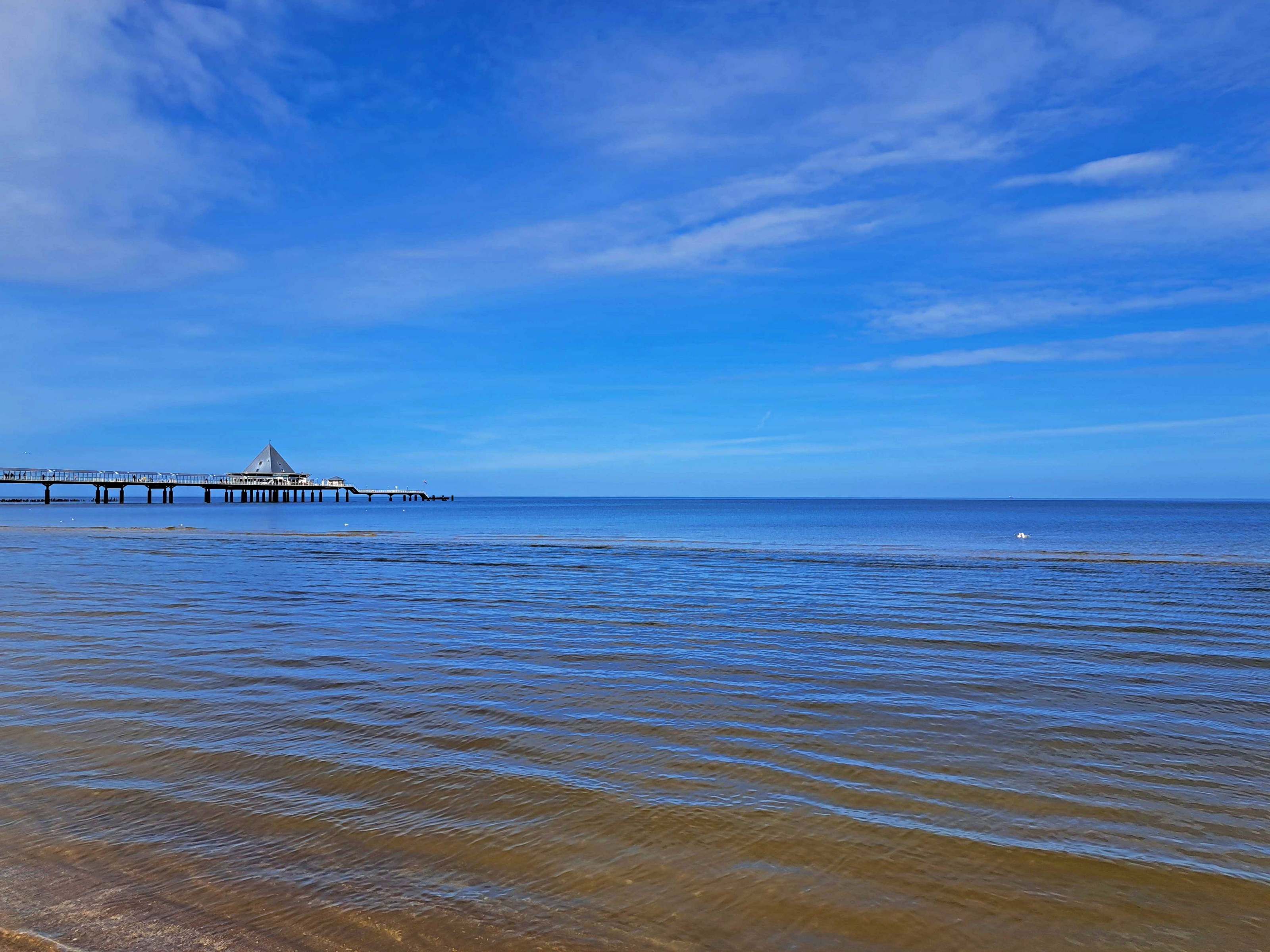 A pier extending into calm waters under a clear sky.
