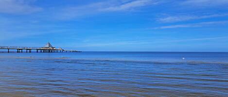 A pier extending into calm waters under a clear sky.