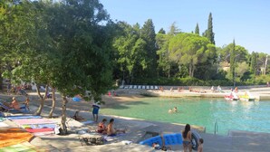 A poolside area with lounge chairs, umbrellas, and inflatable toys. - Holiday flat with air conditioning and balcony (Malinska)