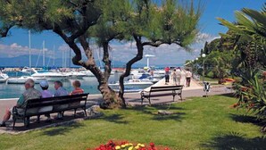 A marina with boats, a tree-lined walkway, and a bench. - Holiday flat with air conditioning and balcony (Malinska)