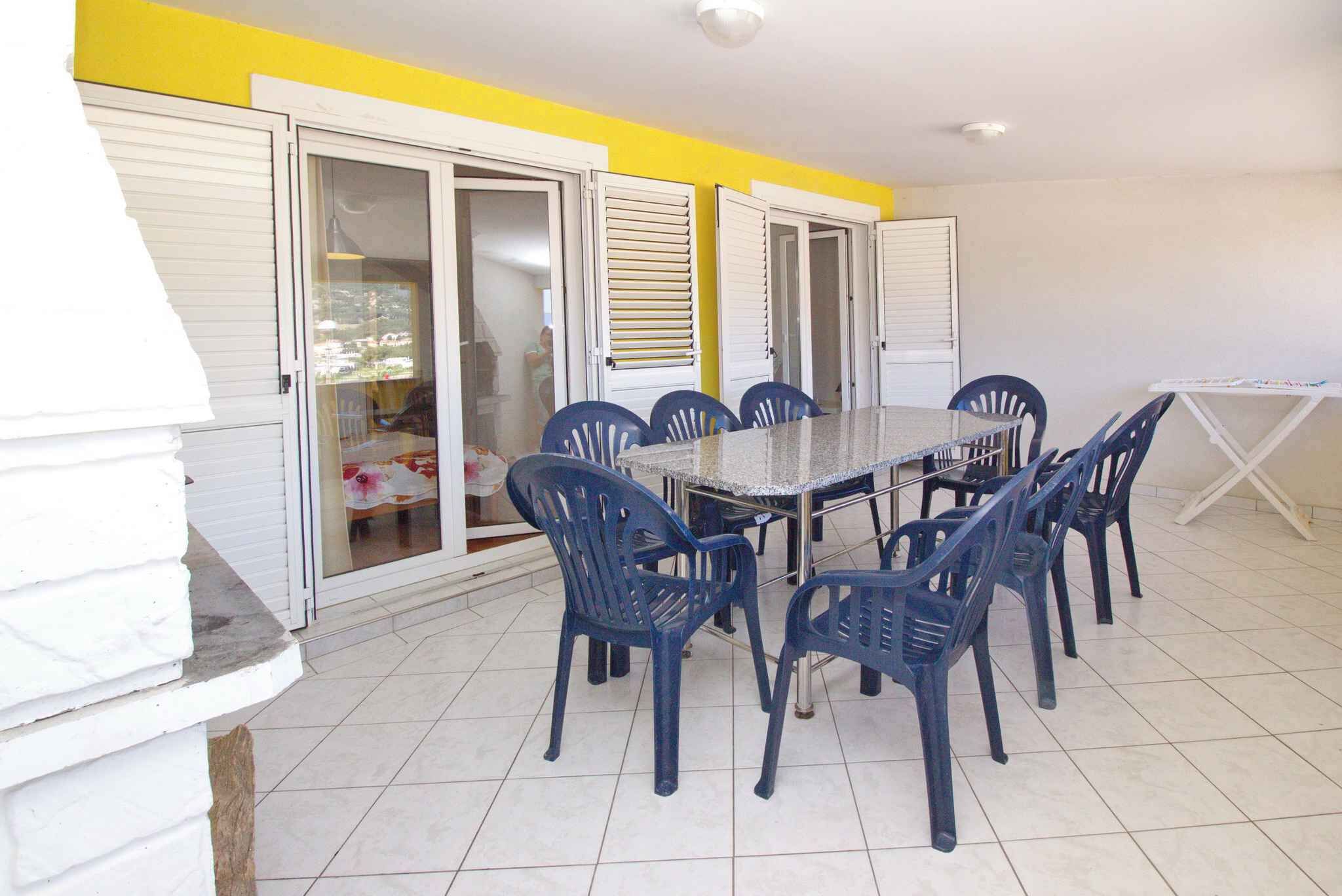 A dining area with a table and chairs, a white exterior wall, and a yellow accent wall.