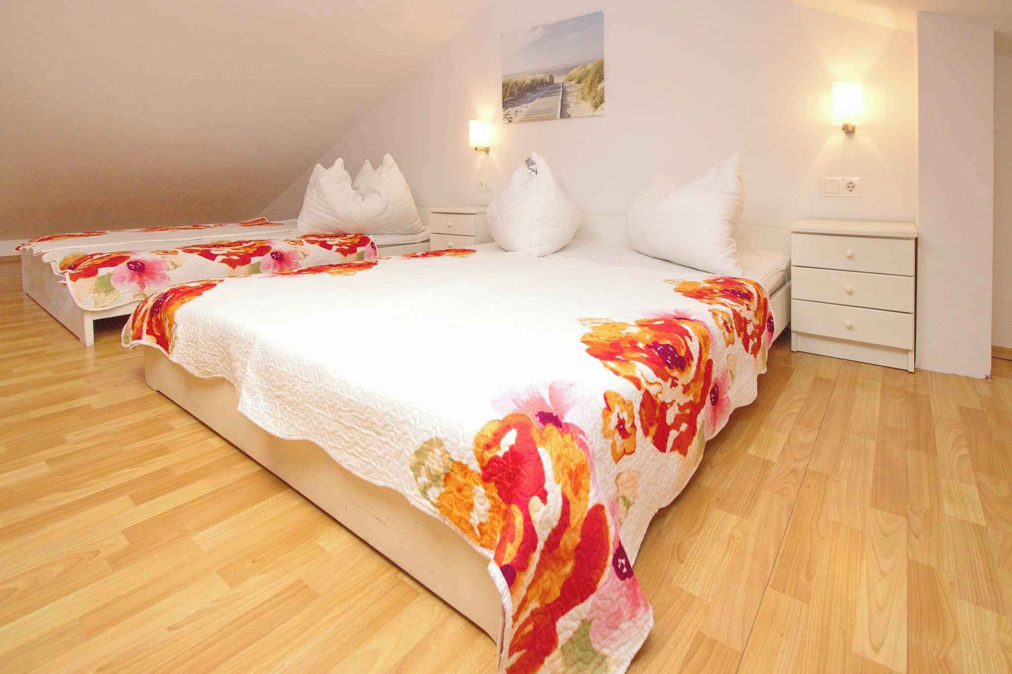 Une chambre avec un grand lit, deux tables de chevet et une lampe fixée au mur.