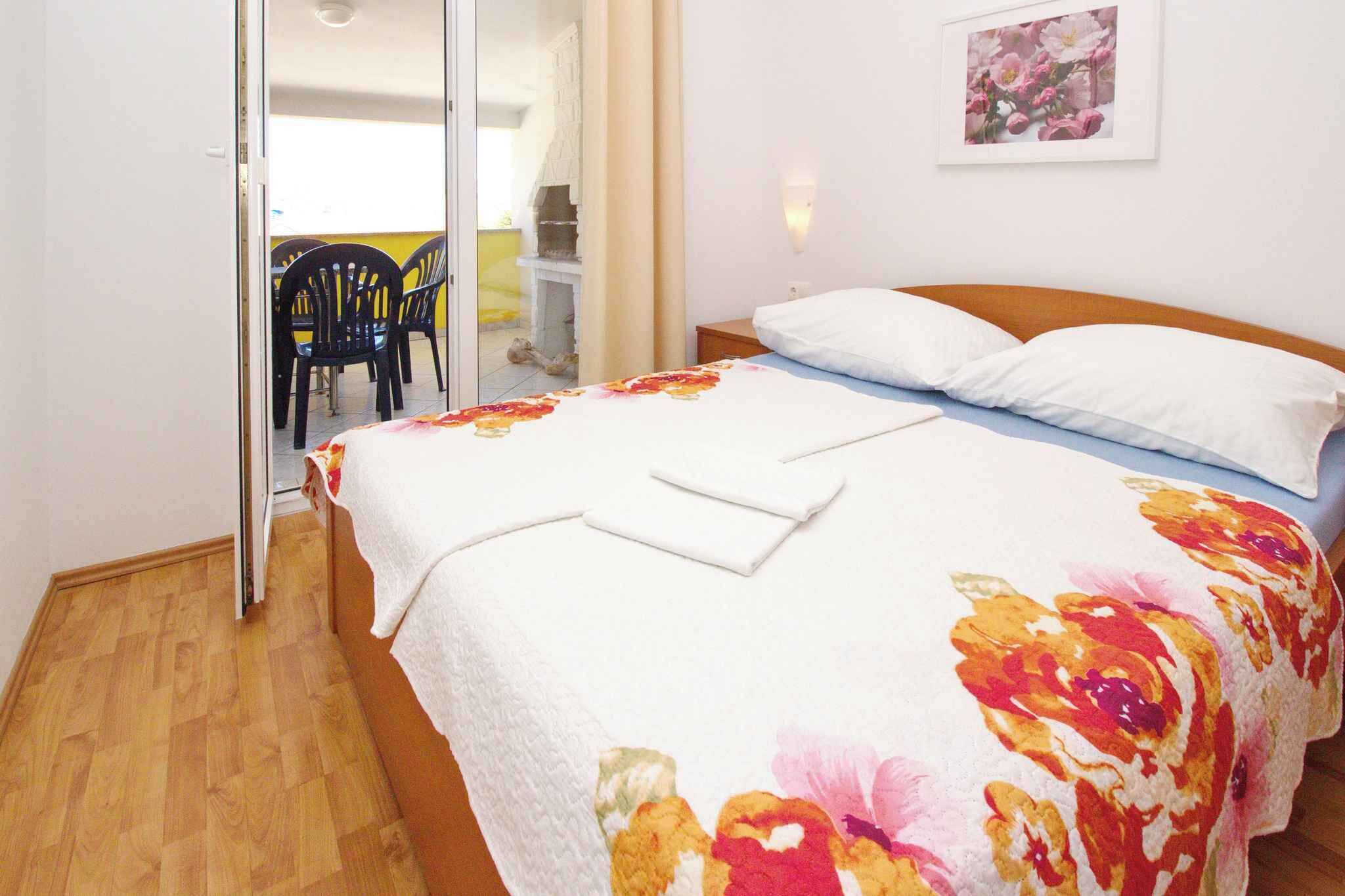 Une chambre à coucher comprenant un lit, une table de chevet, une chaise et une porte donnant sur un balcon.
