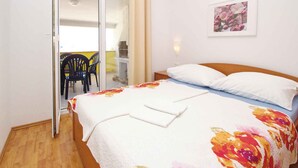 Ein Schlafzimmer mit einem Bett, einem Nachttisch, einem Sessel und einer Tür, die auf einen Balkon führt.