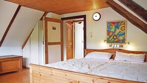 Un dormitorio con una cama de madera, un aparador de madera, una puerta y un cuadro colorido en la pared.