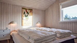 Un dormitorio con una cama, dos mesitas de noche, un cartel en la pared y una ventana.