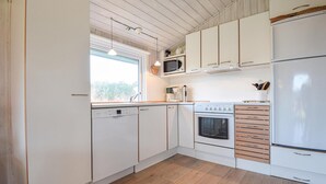 Una cocina con armarios blancos, lavavajillas, microondas, estufa y refrigerador.