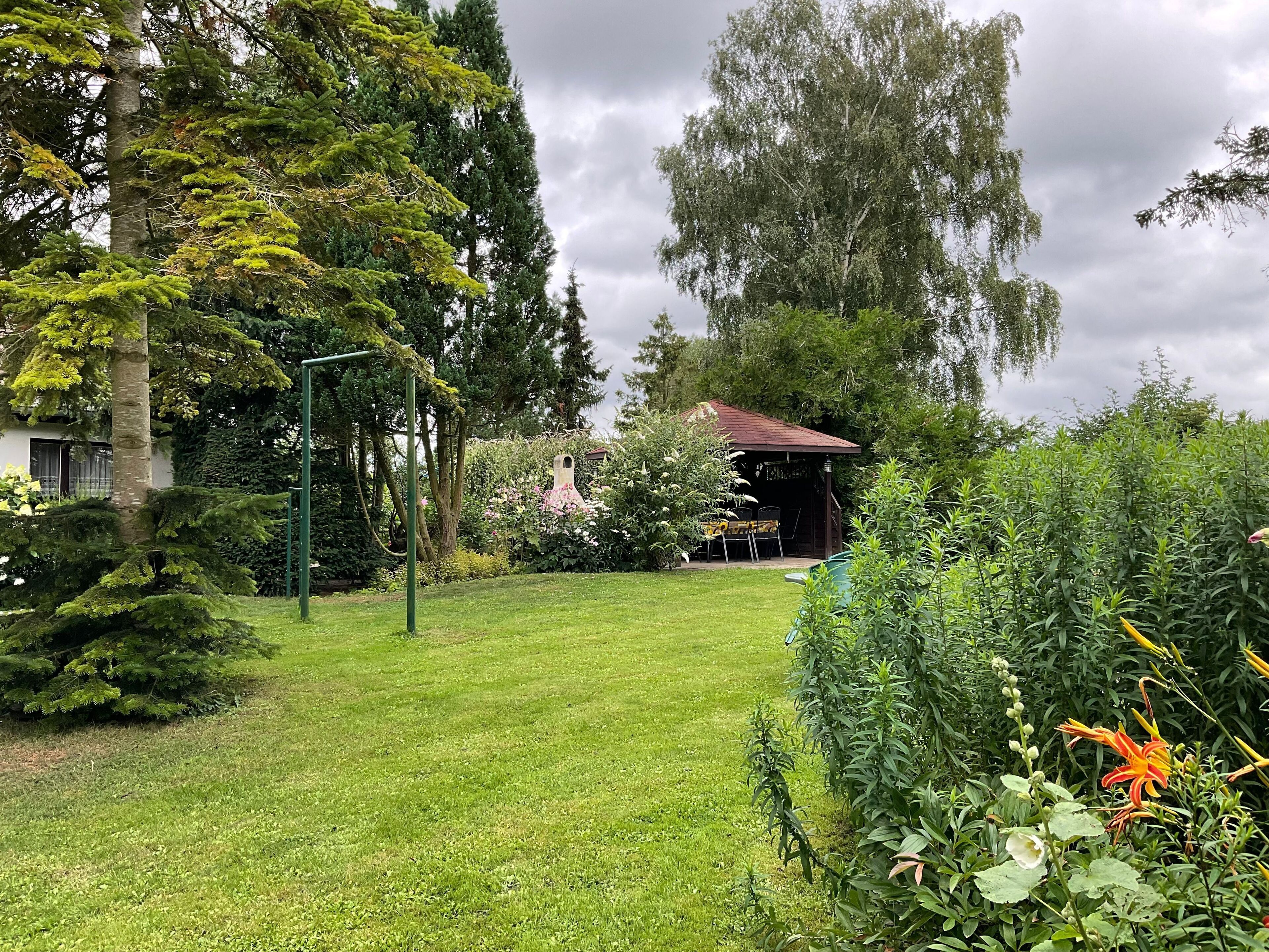 Un jardin bien entretenu, agrémenté d’un belvédère, d’une statue et de diverses plantes.