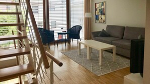 Een moderne woonkamer met een bank, twee stoelen, een salontafel en een trap.