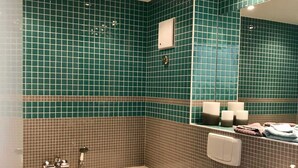 Een badkamer met een bad, toilet en wastafel, alles betegeld in het groen.