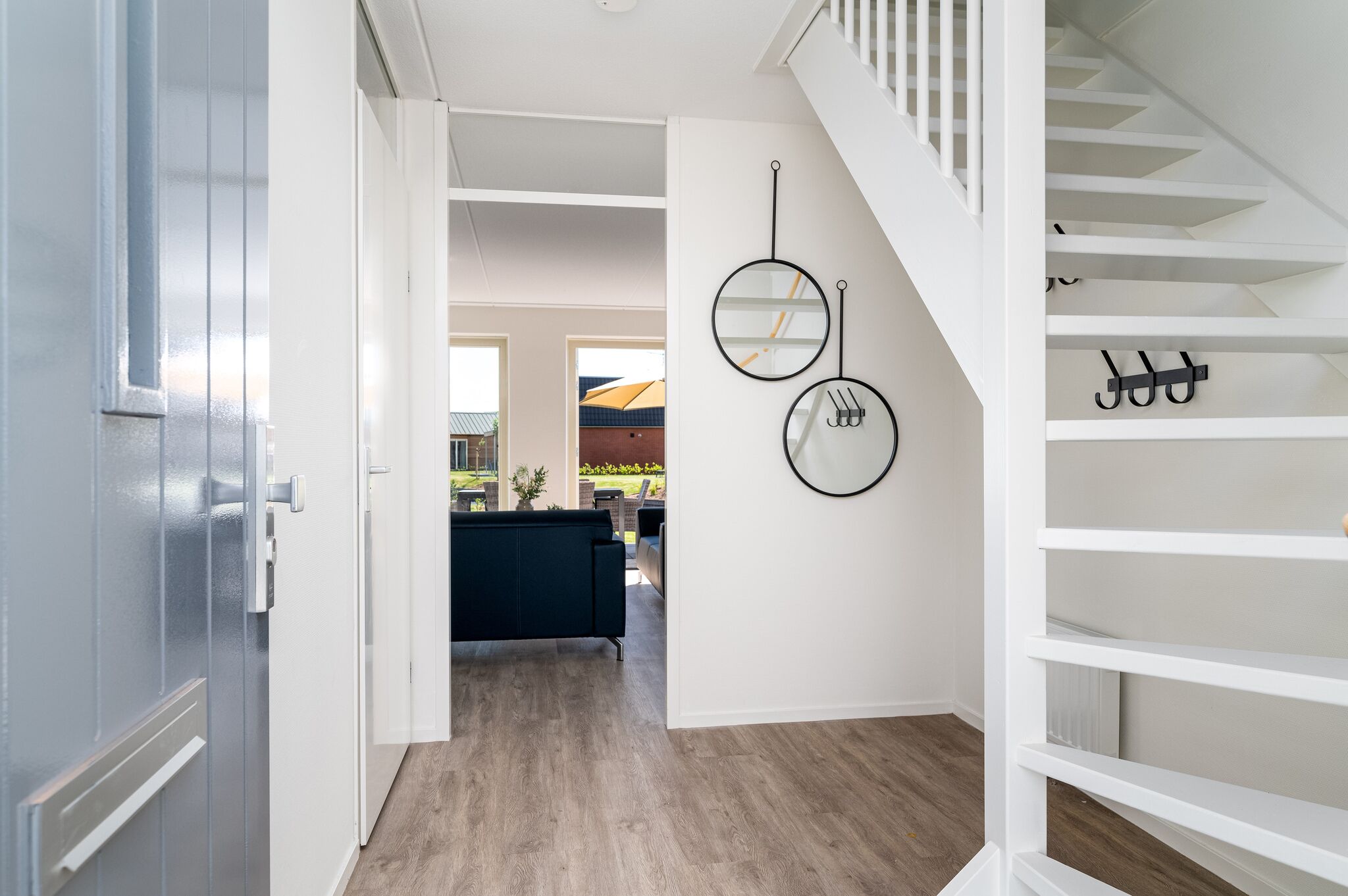 Ein Flur mit Treppe, einem dunkelgrauen Sofa und zwei Wanduhren.