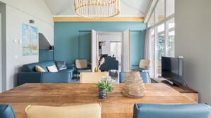 A modern living room with a wooden dining table, blue sofas, and a television. - Recreatiepark Tusken de Marren (Akkrum)
