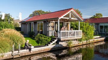 A house with a red-tiled roof, a porch with white railings, and a small garden area.