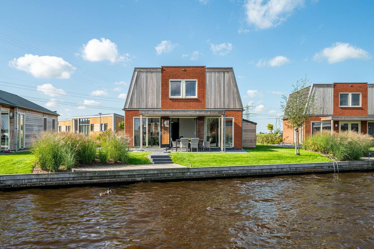 A modern house with a flat roof, a front porch, and a small garden.