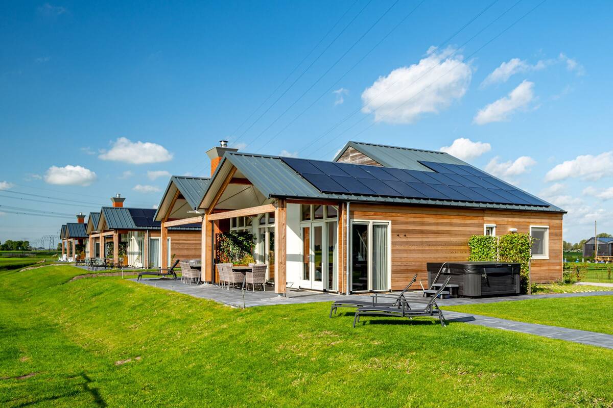A row of modern houses with solar panels, outdoor seating, and a well-maintained lawn.