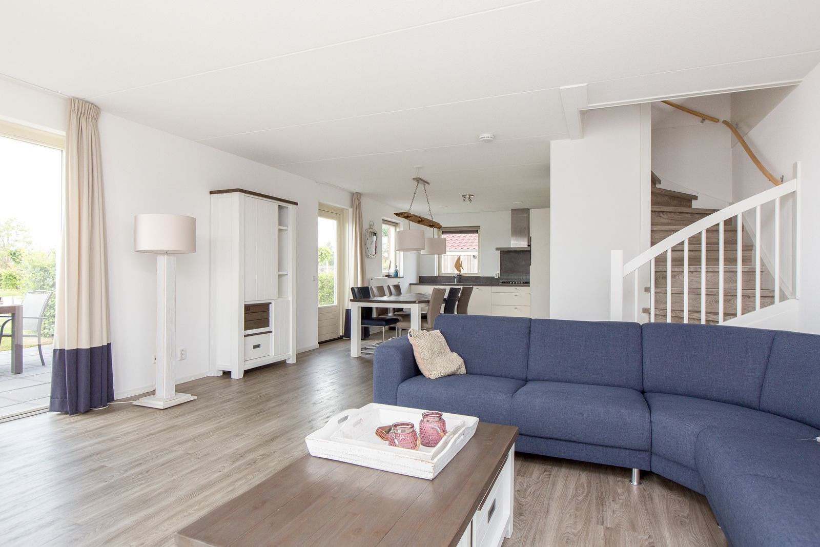 Ein geräumiges Wohnzimmer mit blauem Sofa, Holztisch und Essbereich im Hintergrund.