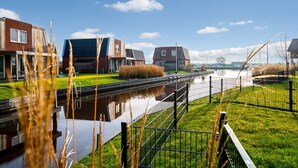 A canal with a lock system, surrounded by grassy areas and modern buildings with large windows. - Recreatiepark Tusken de Marren (Akkrum)