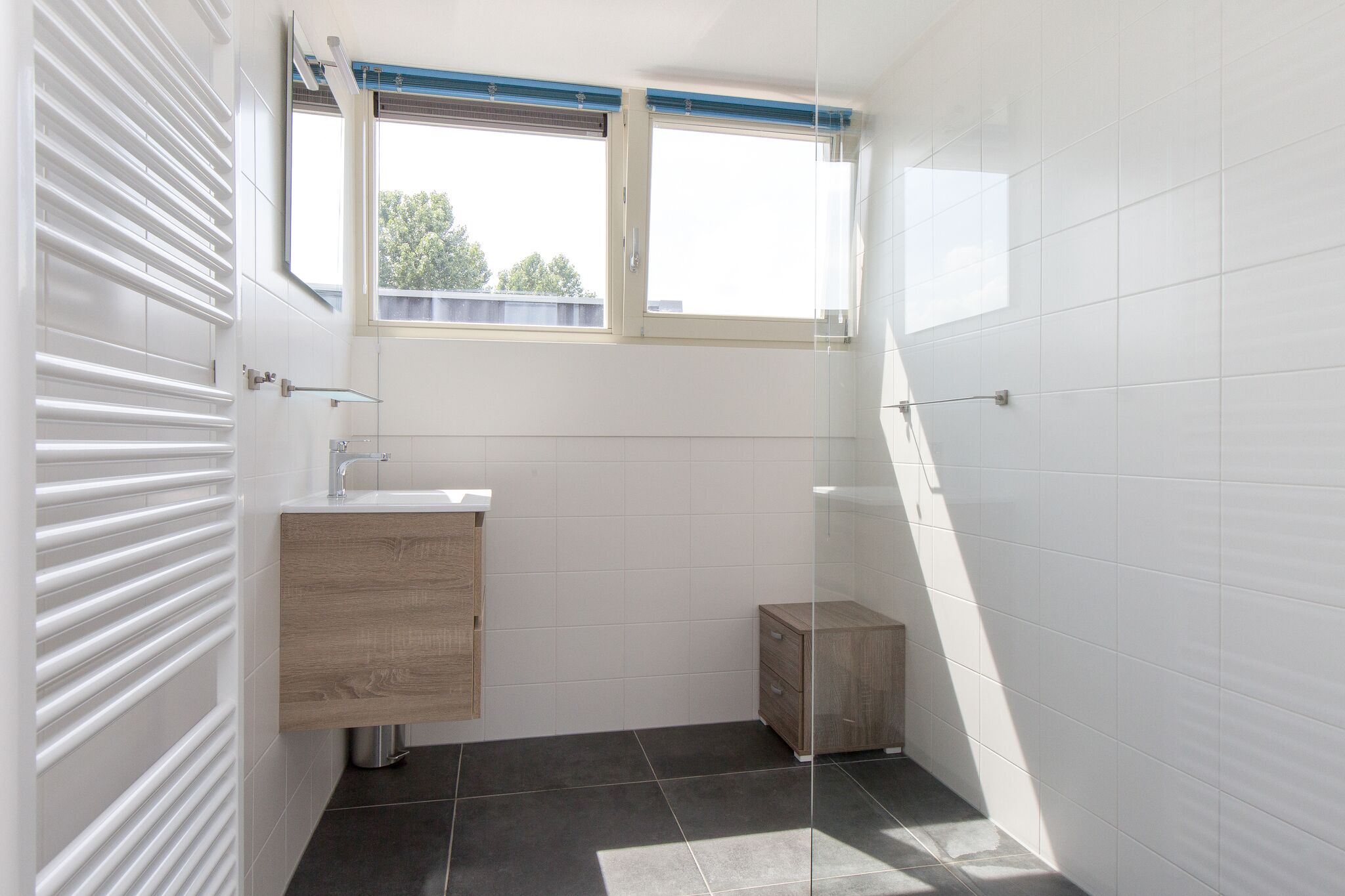 Une salle de bain moderne avec une fenêtre, un lavabo et un meuble.