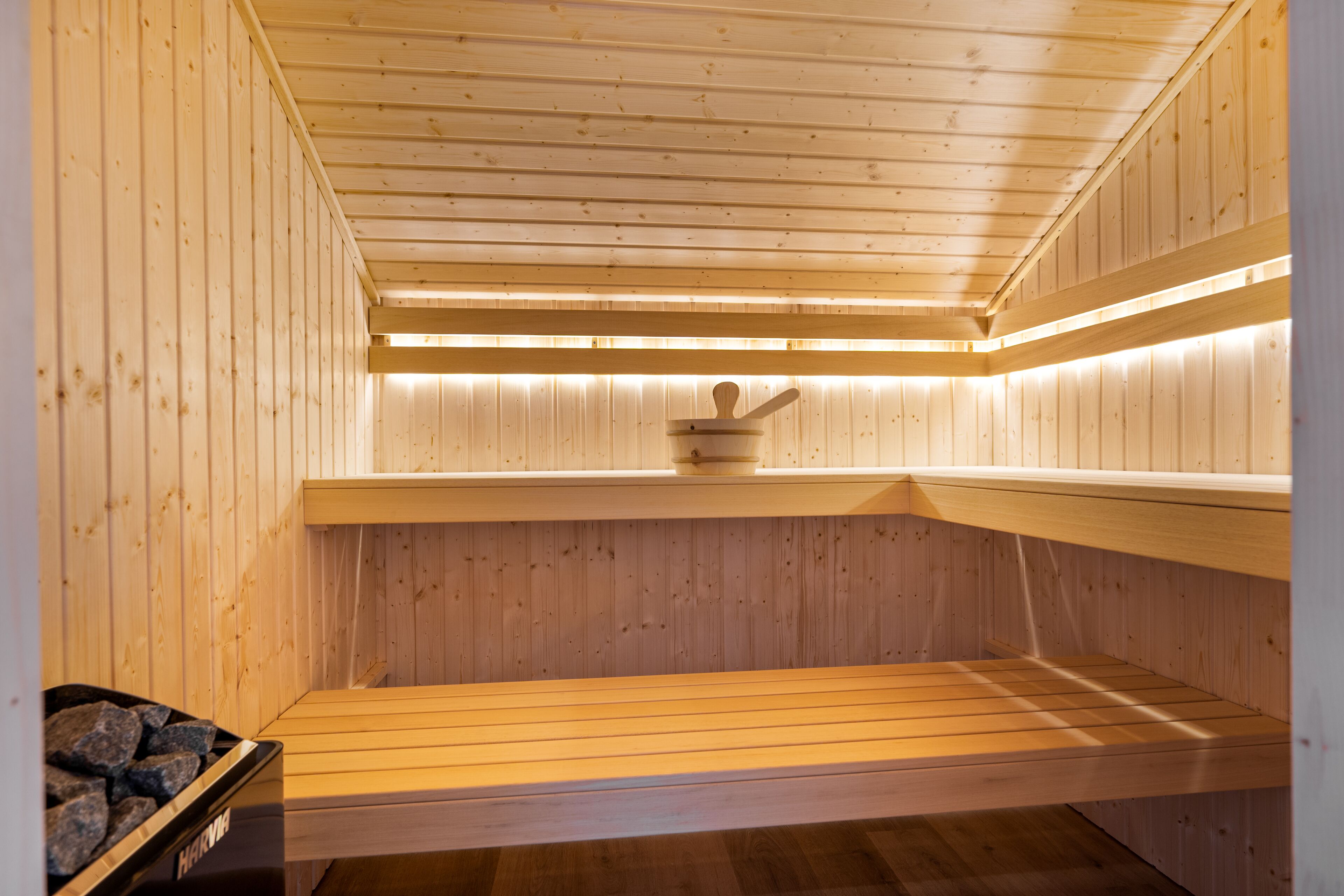 A sauna with wooden walls and benches, a stone bench on the left, and a wooden bench on the right.