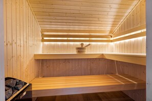 A sauna with wooden walls and benches, a stone bench on the left, and a wooden bench on the right. - Recreatiepark Tusken de Marren (Akkrum)