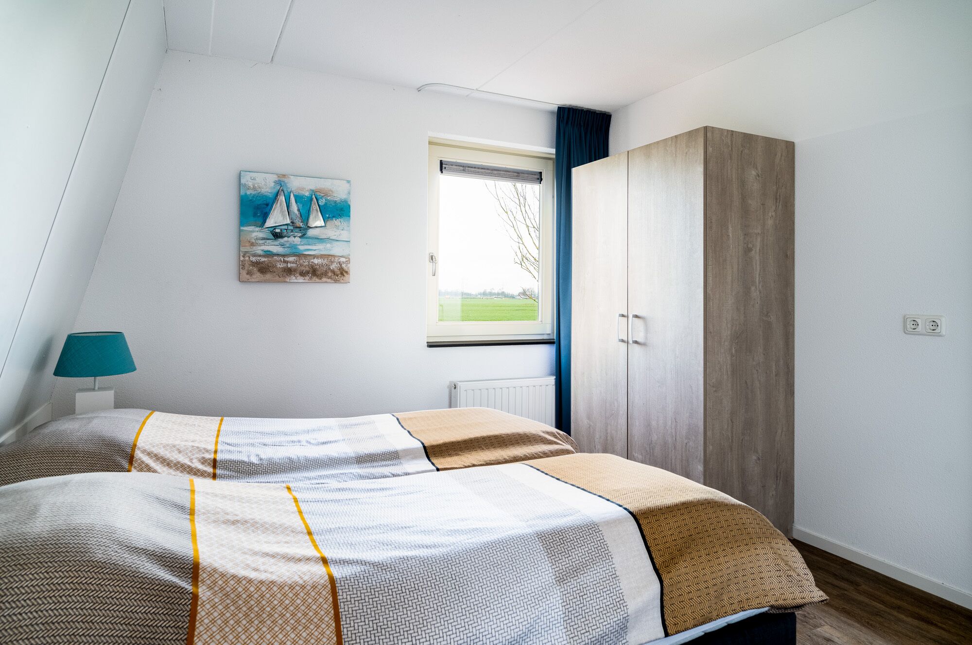 A bedroom with a bed, a painting, a window, and a wardrobe.