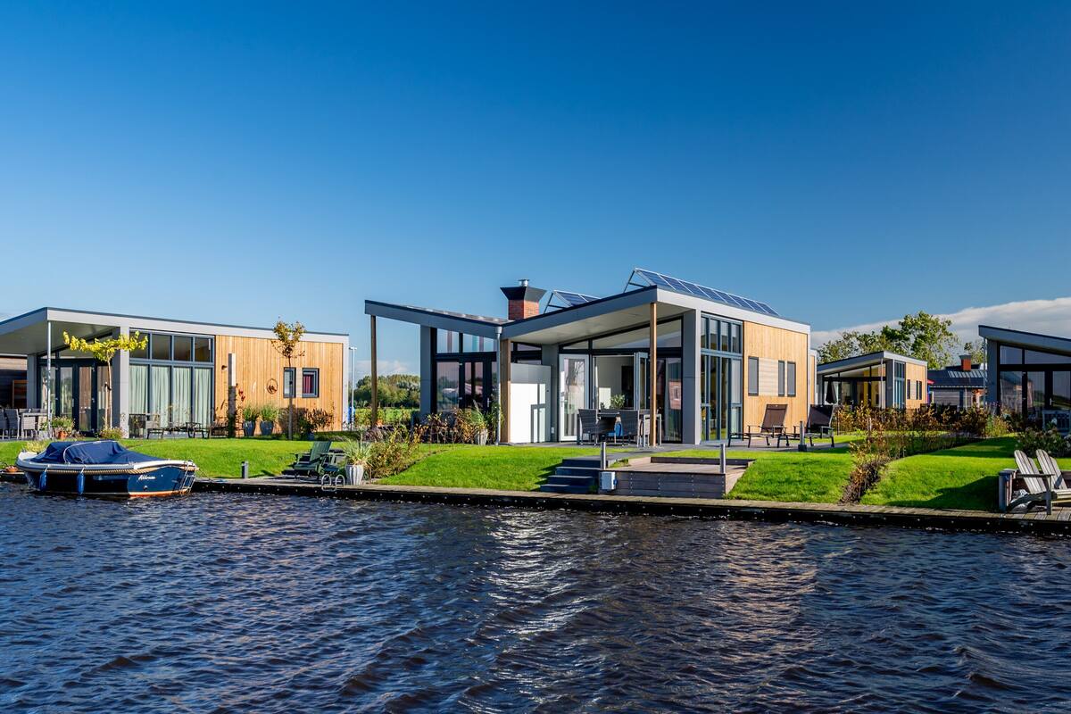 A modern waterfront property with a boat dock, large glass windows, and a well-maintained lawn.