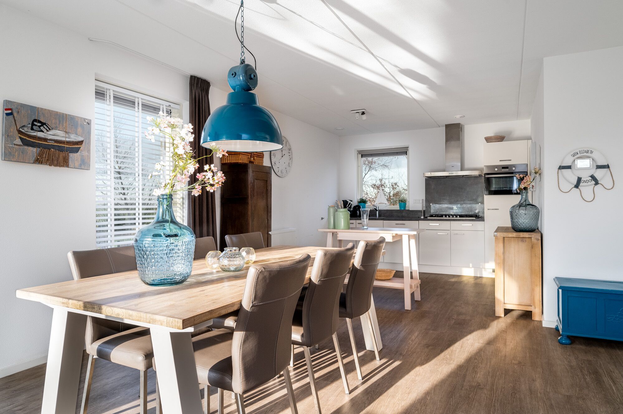 A modern kitchen with a stove, oven, and microwave. There is a dining table with chairs and a vase with flowers.