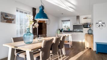 A modern kitchen with a stove, oven, and microwave. There is a dining table with chairs and a vase with flowers.