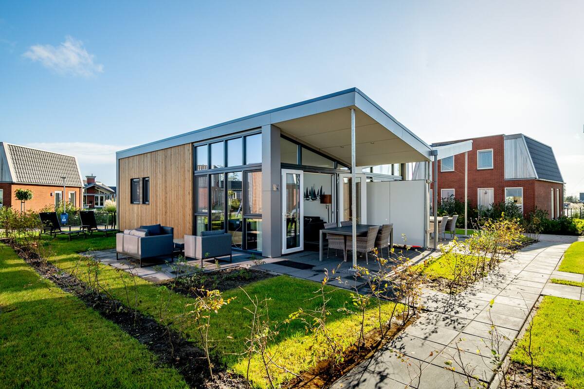 A modern house with a patio area, large windows, and a covered outdoor seating space.