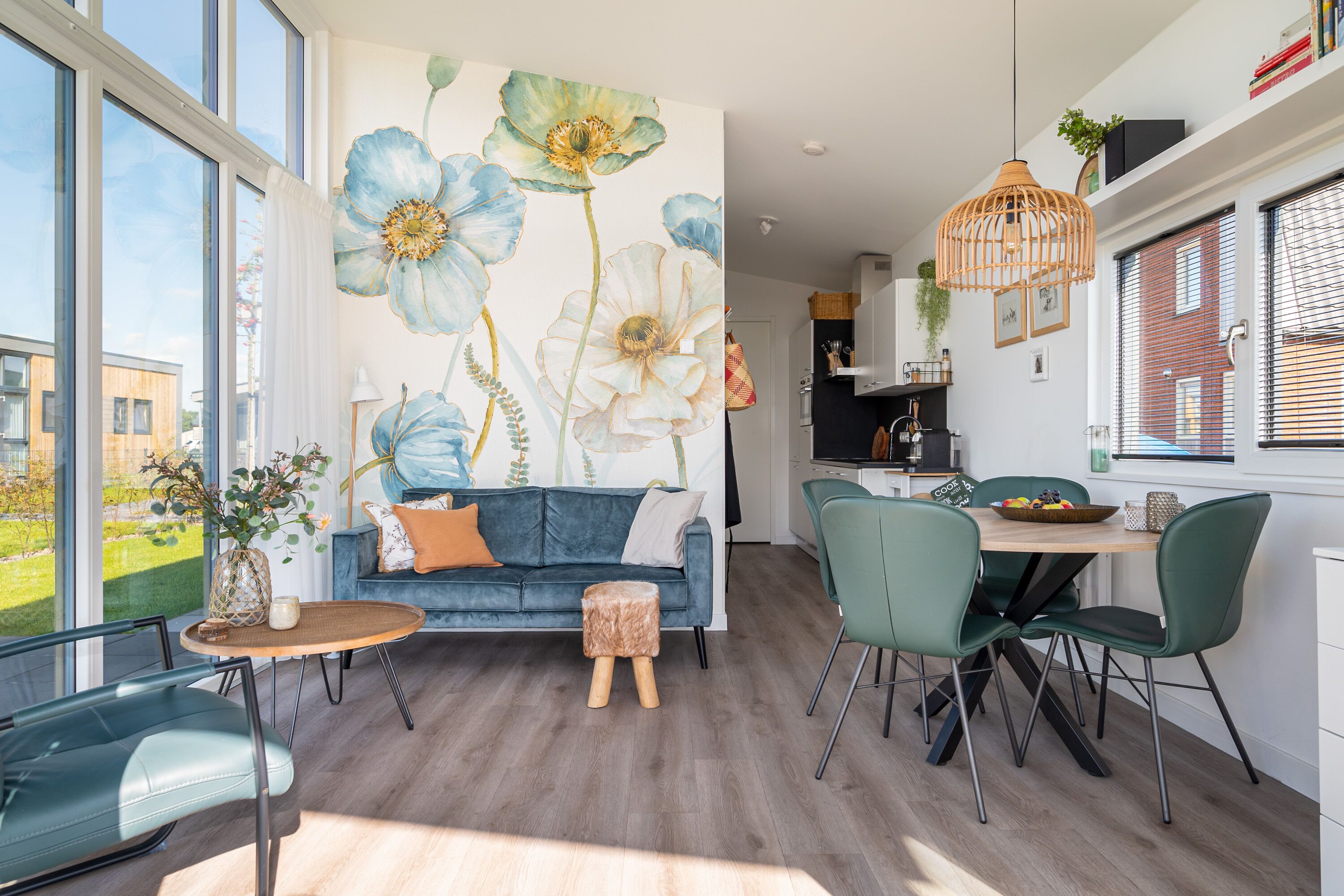 Una sala de estar moderna con un sofá azul, una mesa de comedor con sillas y un ventanal grande.