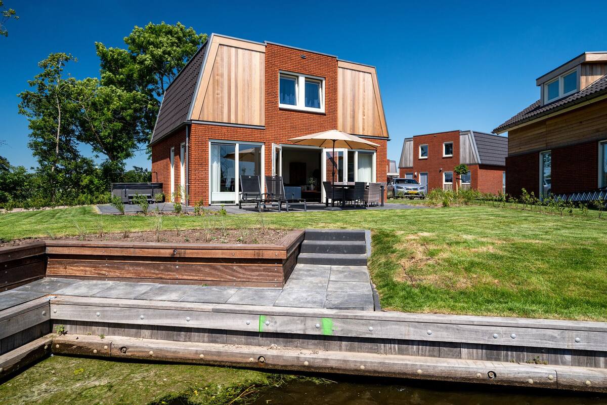 A modern house with a patio, a small deck, and a grassy yard.
