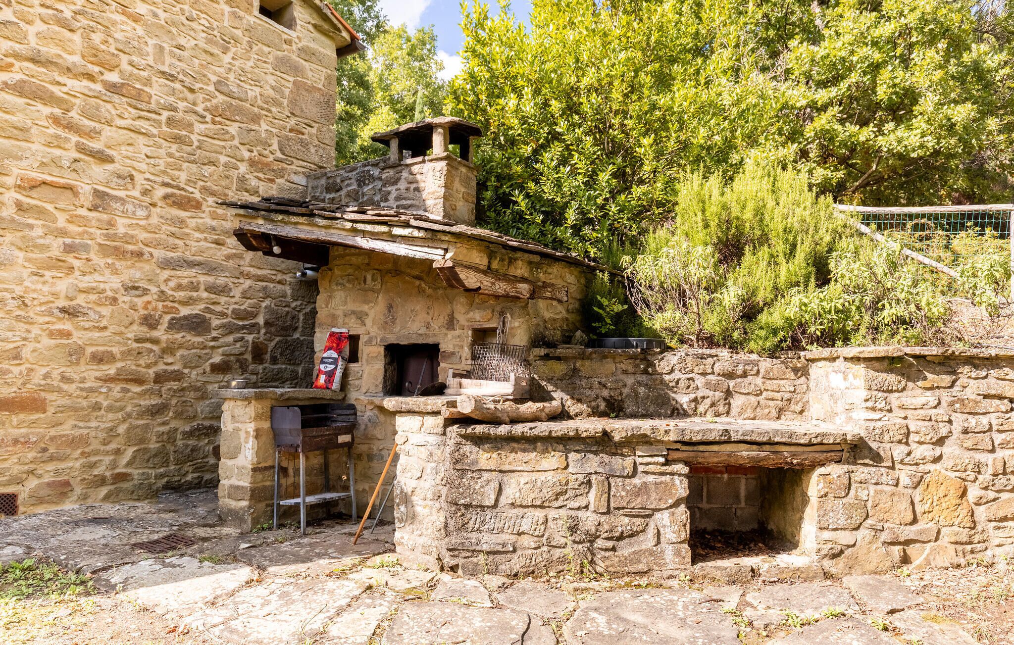 A rustic stone building with a chimney, a small window, and a metal bench.