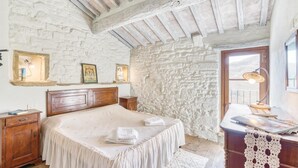 Une chambre à coucher avec un lit en bois, une table de chevet, un bureau avec une lampe et un mur en pierre.