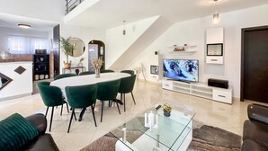 Un salon moderne comprenant un coin repas, un escalier et un téléviseur.