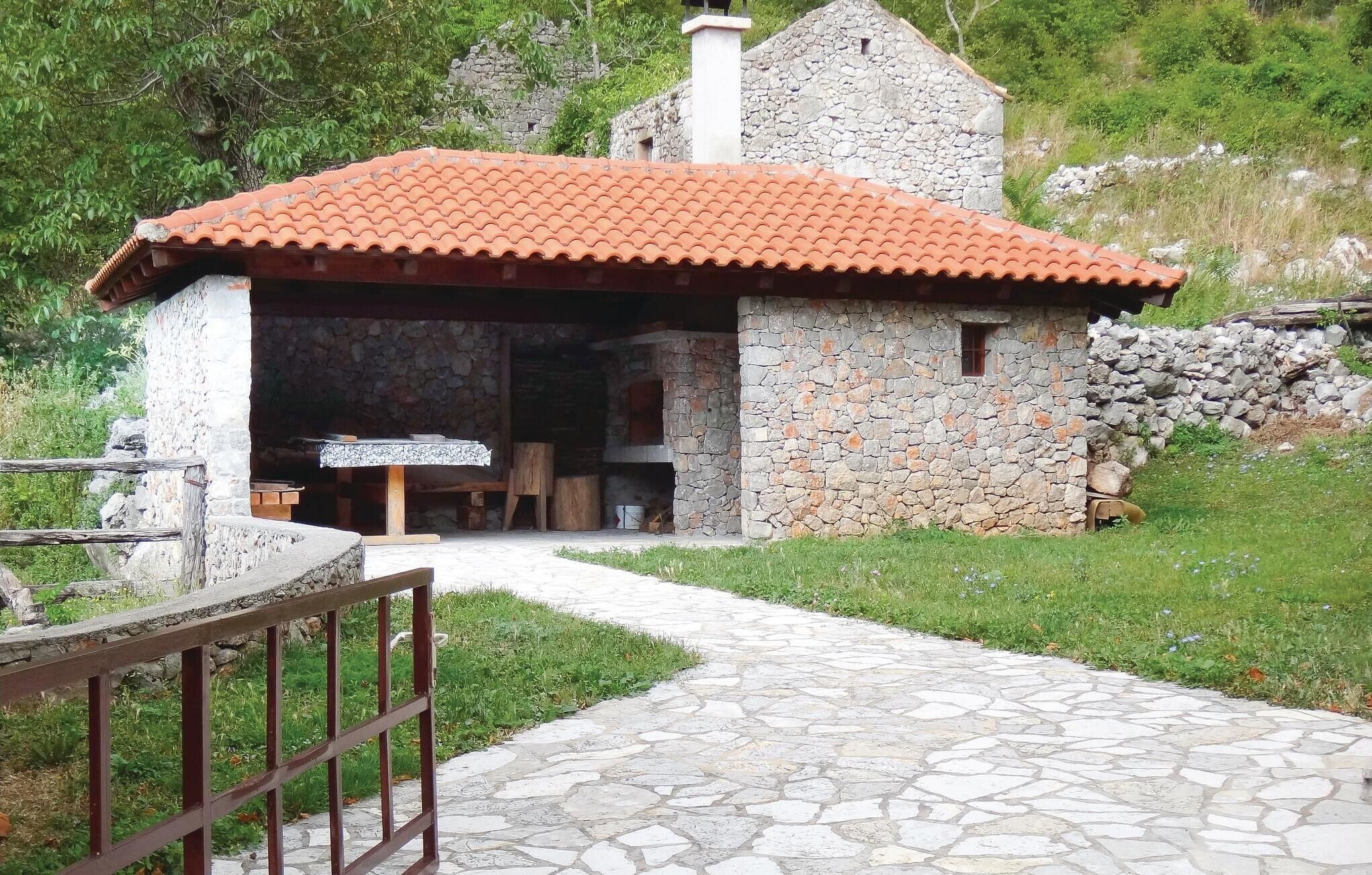 A stone building with a tiled roof, a stone chimney, and a stone wall.