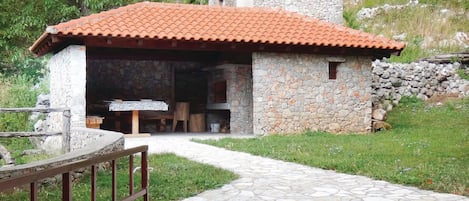 Un edificio de piedra con techo de tejas, chimenea de piedra y una pared de piedra.
